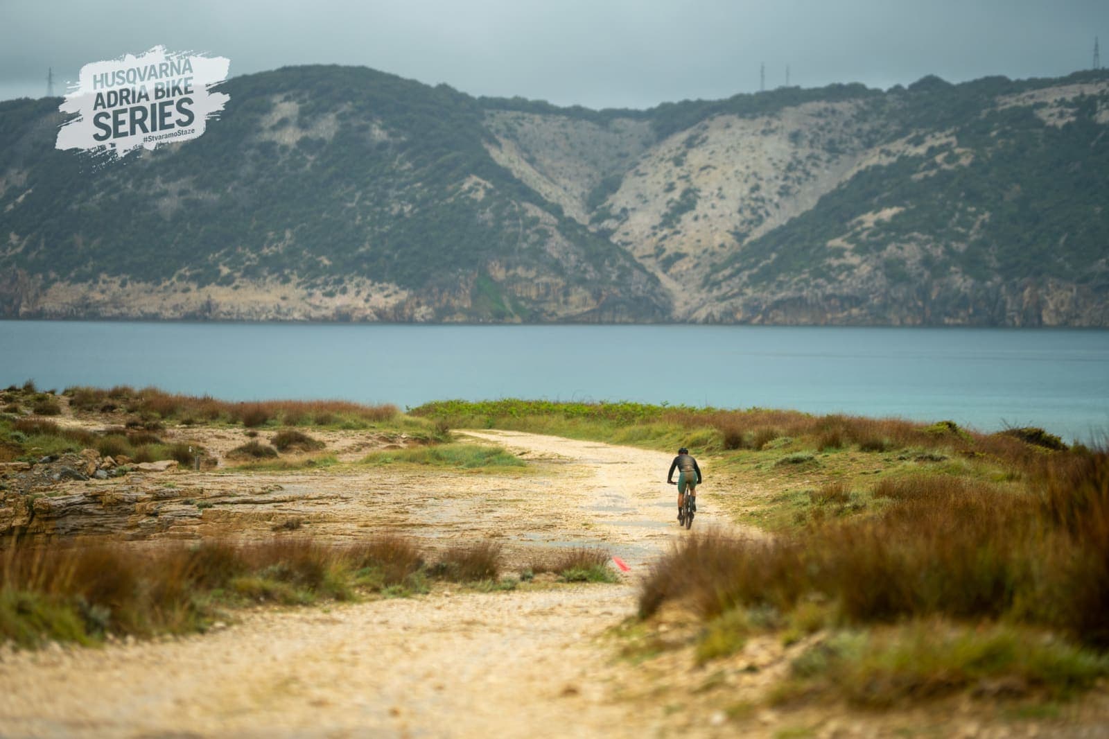 A lone rider descending toward the sea on the Rab MTB Marathon course.
